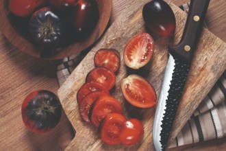 Sliced tomatoes, Black Beauty variety, on a cutting board, top view, on the kitchen table