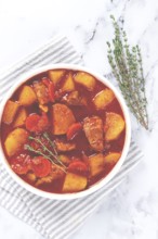 Meat goulash with potatoes and carrots, sweet peppers, in a saucepan, top view, traditional