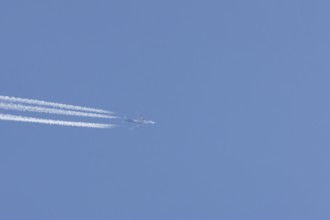 Boeing 747 Jumbo jet passenger aircraft in flight in a blue sky with vapour trails or contrails