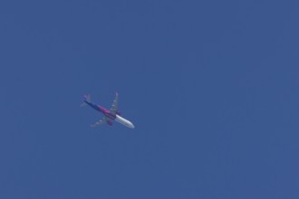 Airbus A321 jet aircraft of Wizz Air airlines in flight in a blue sky, England, United Kingdom