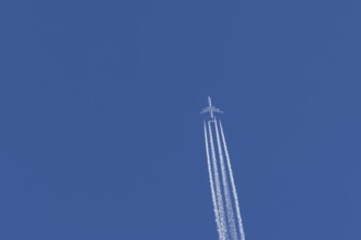 Airbus A340-300 jet aircraft of Lufthansa airlines in flight in a blue sky with vapour trails or