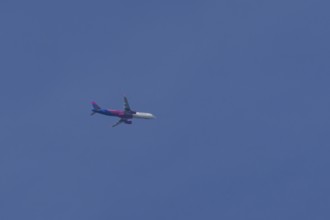 Airbus A321 jet aircraft of Wizz Air airlines in flight in a blue sky, England, United Kingdom