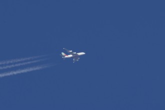 Airbus A380 jet passenger aircraft of Emirates airlines in flight in a blue sky with vapour trails