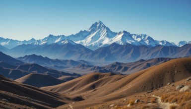Majestic mountain range with snow-capped peaks, layered with rolling hills in shades of brown and