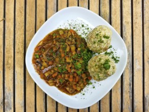 Two dumplings and a vegetable dish on a plate, served on a wooden table Lower Austria Austria