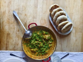 A pot of curry and herbs served with bread on a wooden table Lower Austria Austria