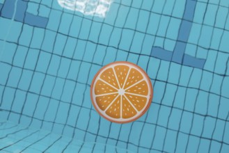 Blue swimming pool from above, an orange tray floats in it