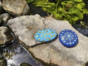 Two decorated stones on a rock by the water with plants in the background Lower Austria Austria