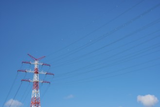 An extremely high electricity electricity electricity pylon, marked white and red, on the banks of