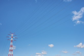 An extremely high electricity electricity electricity pylon, marked white and red, on the banks of