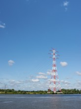 An extremely high electricity electricity electricity pylon, marked white and red, stands on the