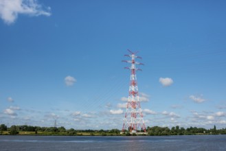 An extremely high electricity electricity electricity pylon, marked white and red, stands on the
