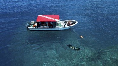 Diver scuba diving swims dives next to diving ship anchored at reef, Pacific Ocean, Yap Island, Yap