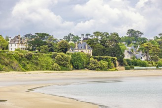 House by a sandy beach by the sea with lush green trees at the coast, Morgat, Crozon peninsula,