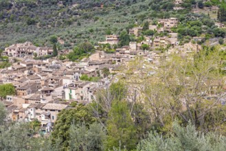 View at an old mountain village with residential houses on a slope with lush green trees,
