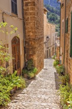 Empty cobblestone alley with beautiful stone houses a sunny hot day in an old spanish village,