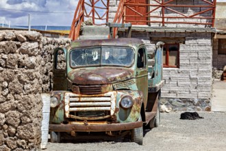 Abandoned rusty lorry in front of a stone building in a peaceful desert landscape, Old lorry in a