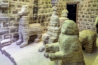 Beige stone sculptures of animals in a rustic room with patterned brick walls, The salt hotel in