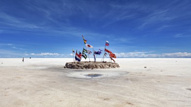 Flags in a vast salt lake under a clear blue sky with scattered clouds, international flags in the