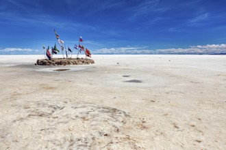 Flags in a vast salt lake under a clear blue sky with scattered clouds, international flags in the