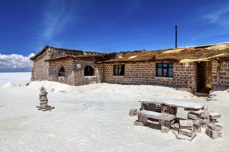 Rustic stone house in a desert-like landscape with blue sky and white ground, the salt hotel in the