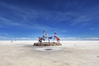 Flags in a vast salt lake under a clear blue sky with scattered clouds, international flags in the
