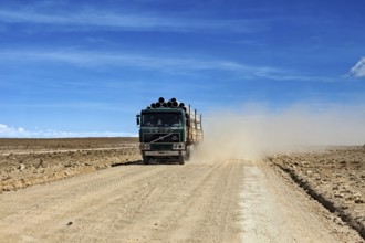 A lorry drives along a dusty road in an arid desert landscape, lorry drives through the highlands