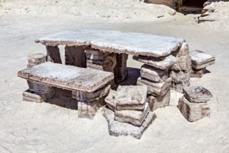 Rustic stone table with benches outdoors on a sandy, white surface, The salt hotel in the salt