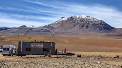 A small migration building in a barren desert landscape with mountains in the background, The small