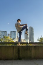 Young martial artist performing the crane pose in a modern city
