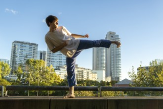 Young man demonstrating a powerful side kick in an urban setting