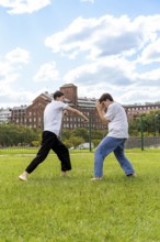 Two young men practicing martial arts in an urban park setting