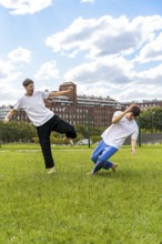 Two young men training martial arts in a green park