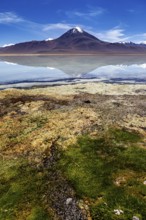 Volcano in front of a clear lake whose surface reflects the summit and the blue sky, The Laguna