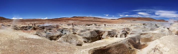 Panoramic view of a geyser field in a barren desert landscape under a bright blue sky, The mud
