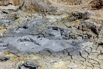 Grey, desolate ground with mud craters and eroded surfaces, the mud volcanoes and fumaroles on the