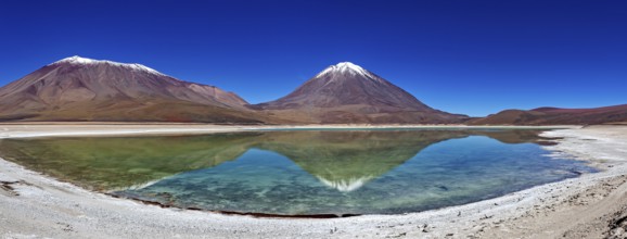 Broad mountain backdrop with two snow-covered peaks reflected in a calm lake, The Laguna Colorada