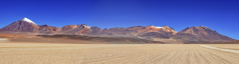 Sweeping panoramic views of a series of mountains, including snow-capped peaks, under a clear sky,
