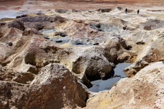 Hot springs with mineral colours in a desert, group of people in the background, The mud volcanoes