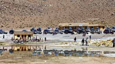 Car park and building in a barren desert landscape with a reflecting lake, The Aguas Termales de