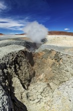 Large crater with steaming geyser in a rocky desert landscape, The mud volcanoes and fumaroles on