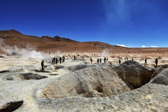 People at a smoking geyser in a vast desert landscape, The mud volcanoes and fumaroles on the