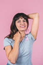 Happy young woman supporting breast cancer awareness with pink ribbon