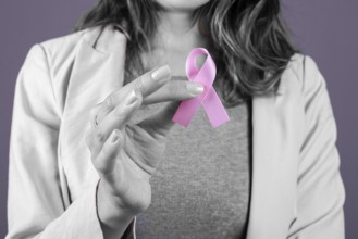 Woman holding a pink breast cancer ribbon, selective color on ribbon only