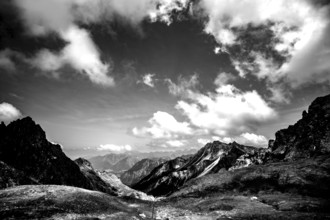Dramatic black and white image of a rocky mountain landscape under a cloudy sky. Kleinwalsertal