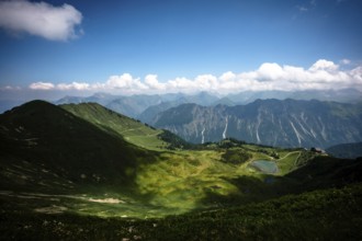 A wide mountain landscape with a valley, blue sky and clouds. Kleinwalsertal Vorarlberg Austria