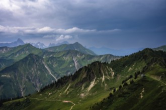 Green hills and mountains under a cloudy sky with far-reaching views. Kleinwalsertal Vorarlberg