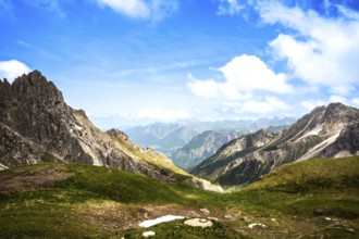 Sweeping views over green valleys and rocky mountains under a clear blue sky. Kleinwalsertal
