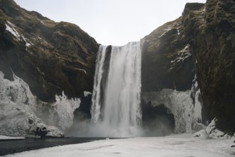 The mighty Skogafoss waterfall in winter. Roaring masses of water meet ice and rock. Skogar,