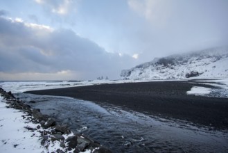 A black beach cuts through white stilts. A coastline like a painting. Renisfjara, Iceland
